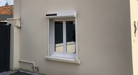 Maison deux étages avec menuiseries SJH, volets bois et caméra sécurité.