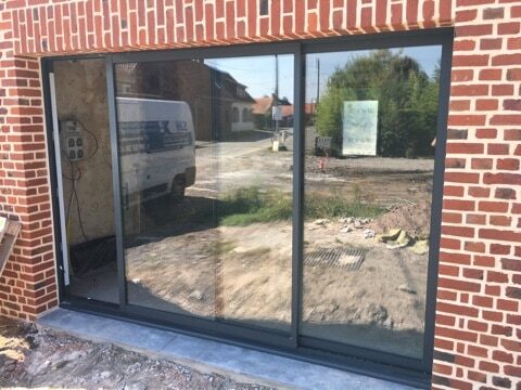 Installation robuste d'une grande fenêtre en verre par SJH Menuiserie, améliorant esthétiquement et fonctionnellement le bâtiment.