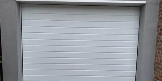 Porte de garage PVC moderne installée dans cadre en béton par SJH Menuiserie.