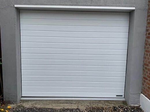 Porte de garage PVC moderne installée dans cadre en béton par SJH Menuiserie.