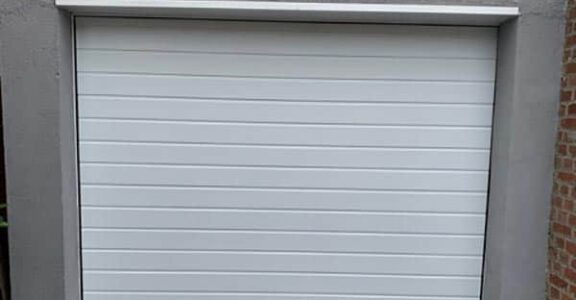 Porte de garage PVC moderne installée dans cadre en béton par SJH Menuiserie.